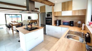 Une cuisine moderne dotée d’un îlot central, de meubles en bois, d’un four encastré et d’un four à micro-ondes.