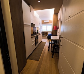 A modern kitchen with a central island, a dining area with a table and chairs, and a view of the living room through an open door. - Delizioso Appartamento Metro A Appia Nuova Colli Albani Parco Della Caffarella (Roma)
