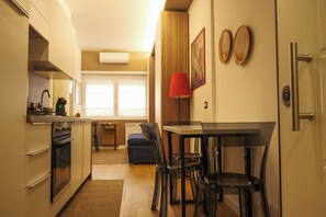 A compact kitchen with a dining area, a red lamp, and a window with blinds. - Delizioso Appartamento Metro A Appia Nuova Colli Albani Parco Della Caffarella (Roma)