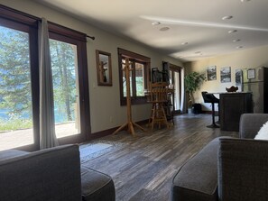 A spacious room with large windows, a wooden dining table, and a seating area with chairs. - 1 BR Lakeview, 5 Mins to Glacier (West Glacier)