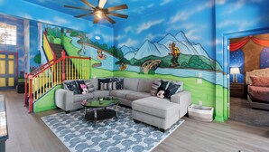 A living room with a mural, a sofa, a coffee table, and a staircase.