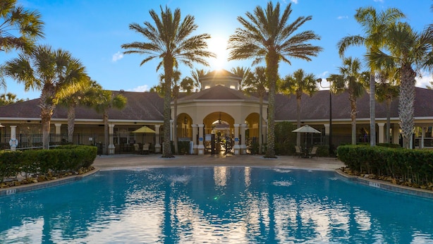 A resort with a central pool, palm trees, and a covered area with arches.