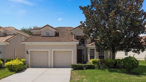 A two-story house with a tiled roof, two attached garages, and a well-maintained lawn.