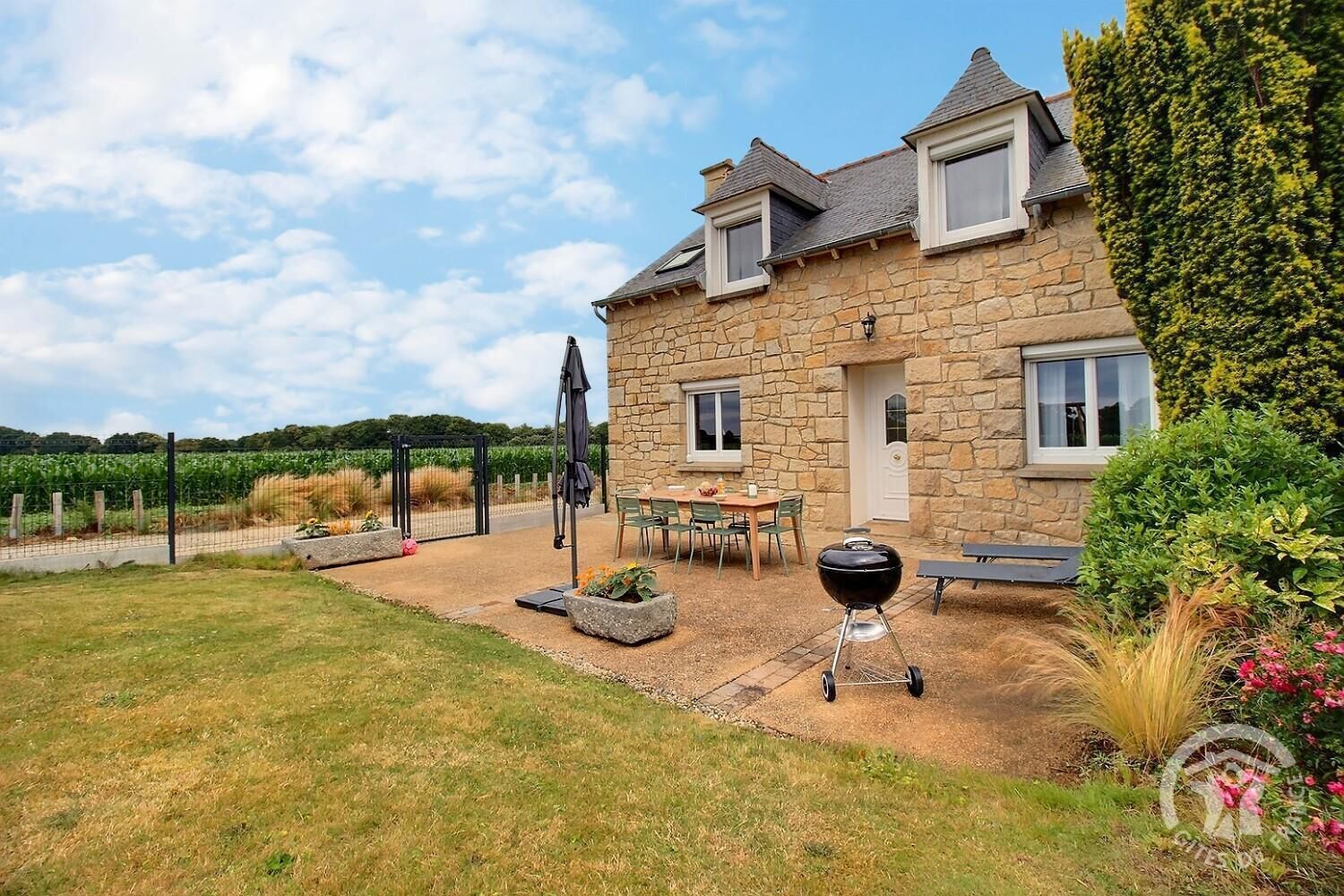 Une maison en pierre avec un patio, un barbecue et une vue sur un vignoble.