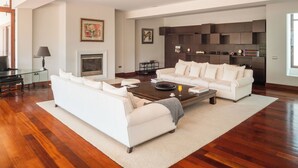 A modern living room with a white sofa, a coffee table, and a fireplace.