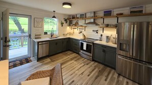 Una cucina moderna con pavimento in legno, elettrodomestici in acciaio inossidabile e un'ampia finestra che si affaccia su un giardino.