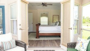 Un dormitorio abierto con una cama, un ventilador de techo y vistas al exterior.