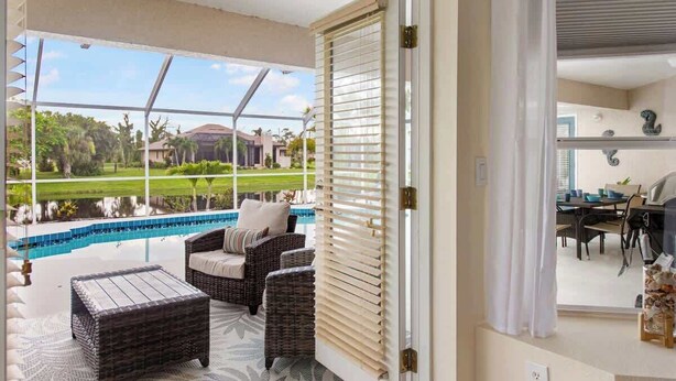 Una habitación con vistas a una piscina, muebles de mimbre y un ventanal corredero.