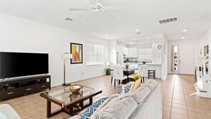 A modern living room with a flat-screen TV, a glass coffee table, and a grey sofa. - Grand Executive Deluxe 4BR Pool Home Near Disney Parks (Davenport)