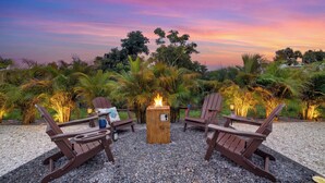 Une vue sur le coucher de soleil, avec un foyer et des chaises longues, dans un cadre de jardin.