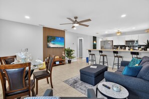A modern living room with a sofa, coffee table, and dining area with chairs.