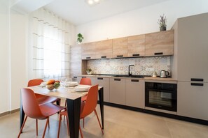 Eine moderne Küche mit Holzschränken, einer gefliesten Spritzschutzwand und einem eingebauten Backofen.