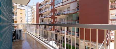 A multi-story residential building with balconies, a tiled floor, and a clear view of the street below.