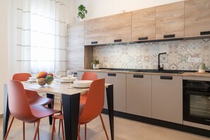 A modern kitchen with a dining area, featuring a central island, built-in cabinets, and a patterned backsplash.