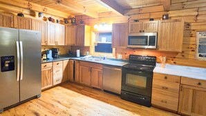 Una cocina tipo cabaña de madera con refrigerador, estufa, microondas y gabinetes de madera.