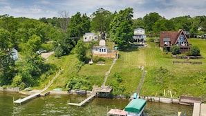 A lakeside property with a dock, a grassy lawn, and several houses.