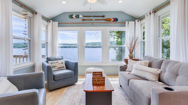 A spacious living room with a view of a lake, a ceiling fan, and a wooden coffee table.