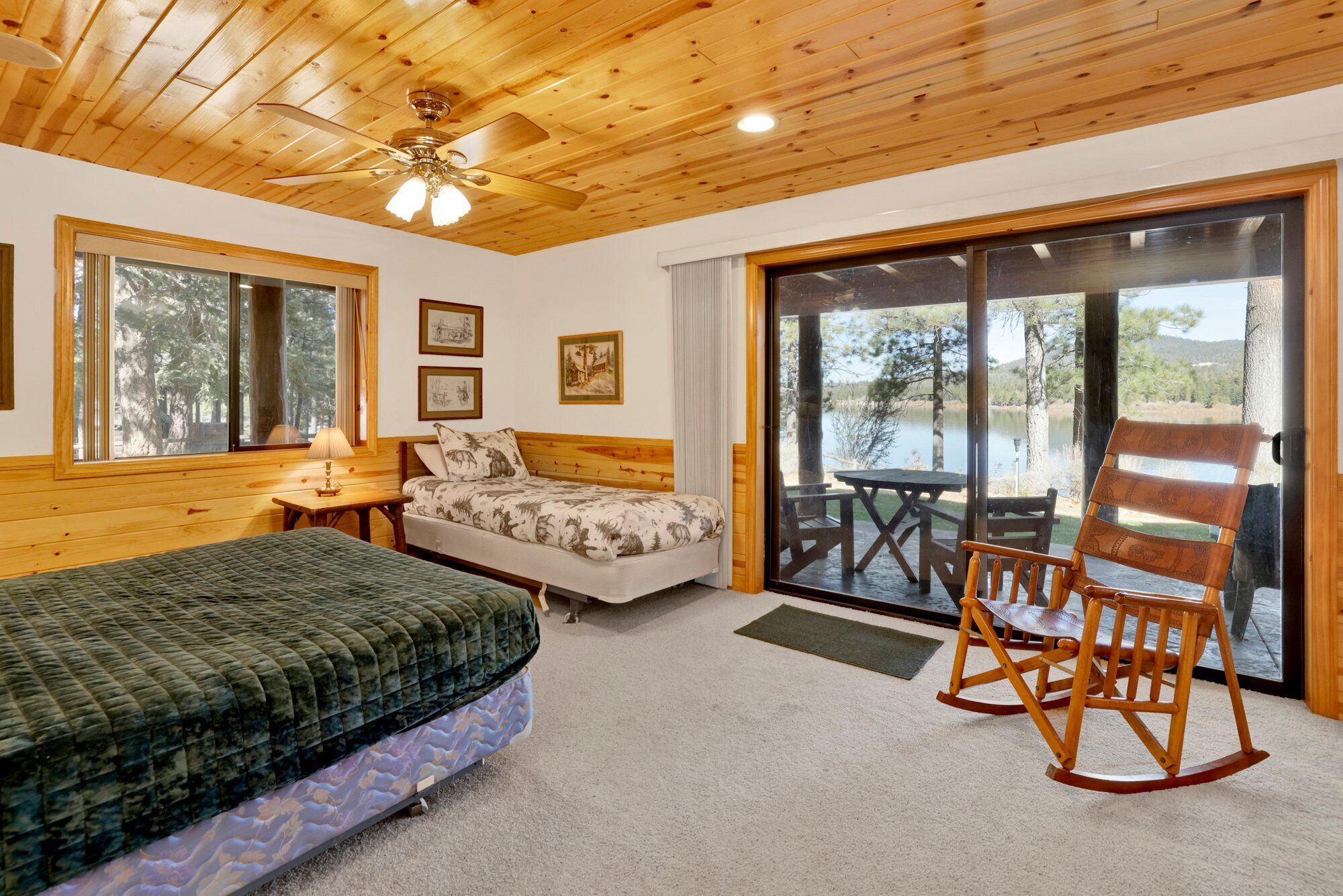 A bedroom with a bed, a chair, a desk, and a window with a view of a lake.