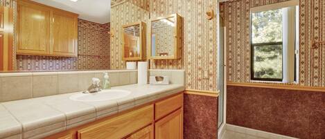A bathroom with wooden cabinets, a sink, and a large mirror.