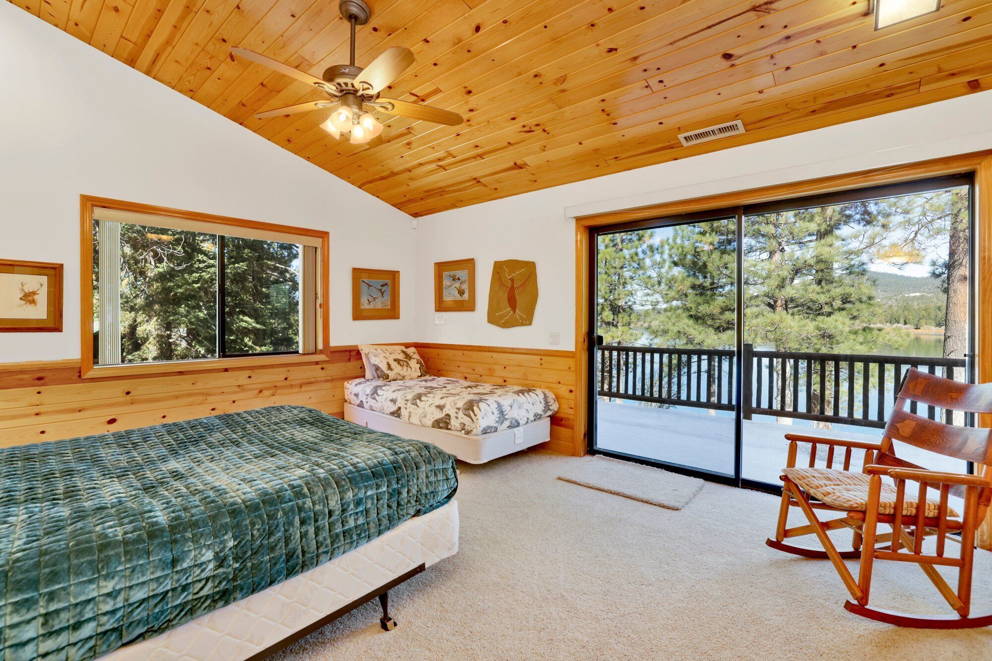 A cabin with two beds, a ceiling fan, and a large sliding glass door leading to a balcony.
