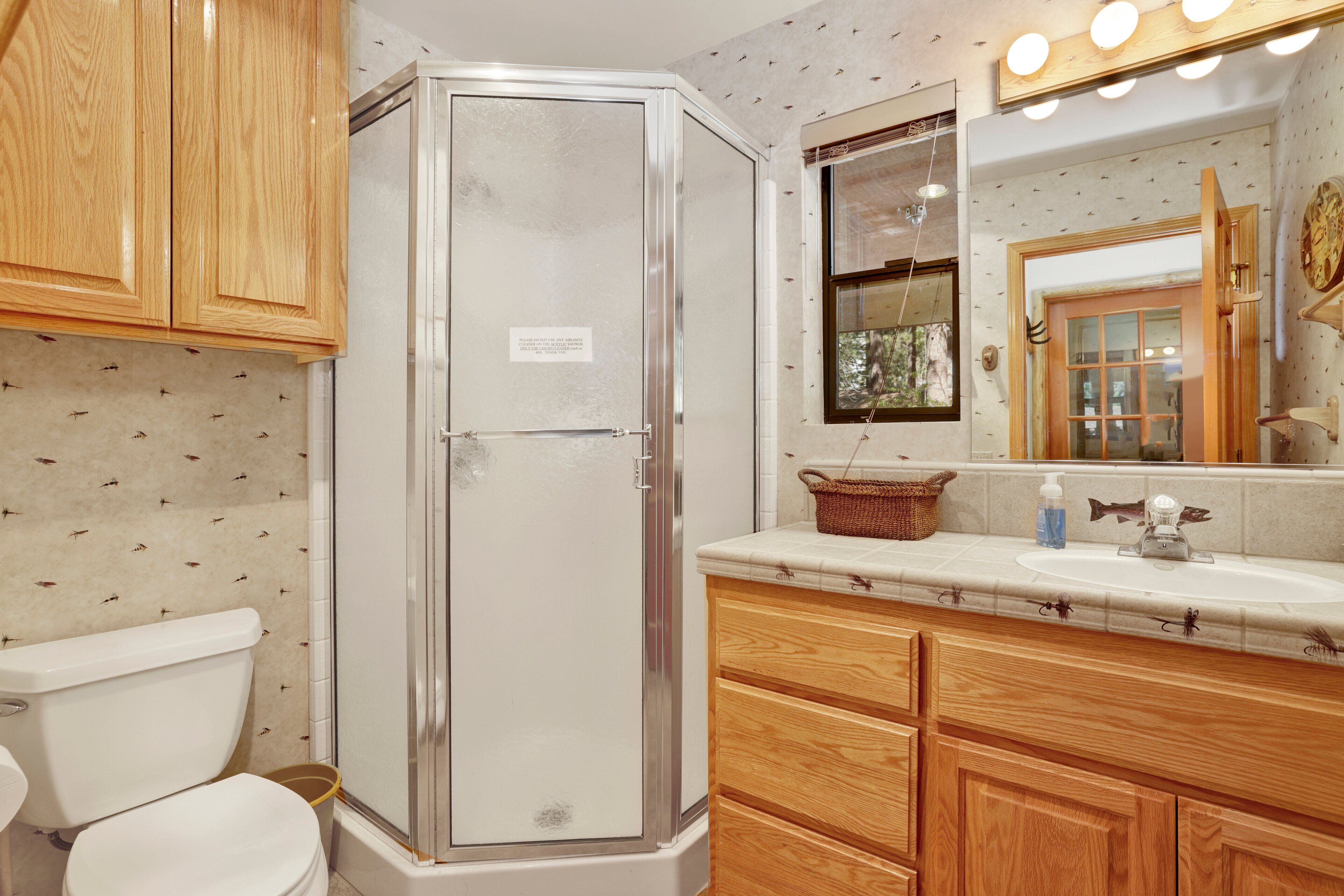 A bathroom with a shower, toilet, and wooden cabinets.