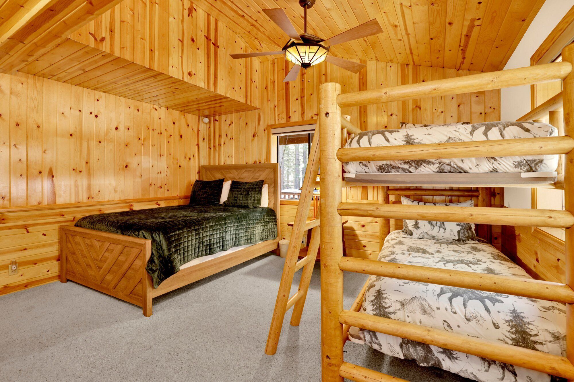 Una habitación de cabaña de madera con literas, una cama individual, un ventilador de techo y una ventana.