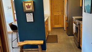 A kitchen with a wooden bench, a refrigerator, and a dining area with a chair.