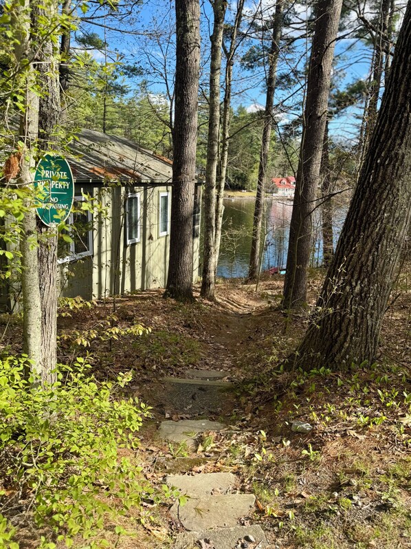 A rustic cabin with a 'PRIVATE PROPERTY NO REPASSING' sign, surrounded by trees and a lake view.