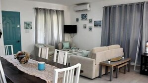 Ett vardagsrum med en soffa, ett matbord med stolar, en tv och ett soffbord.