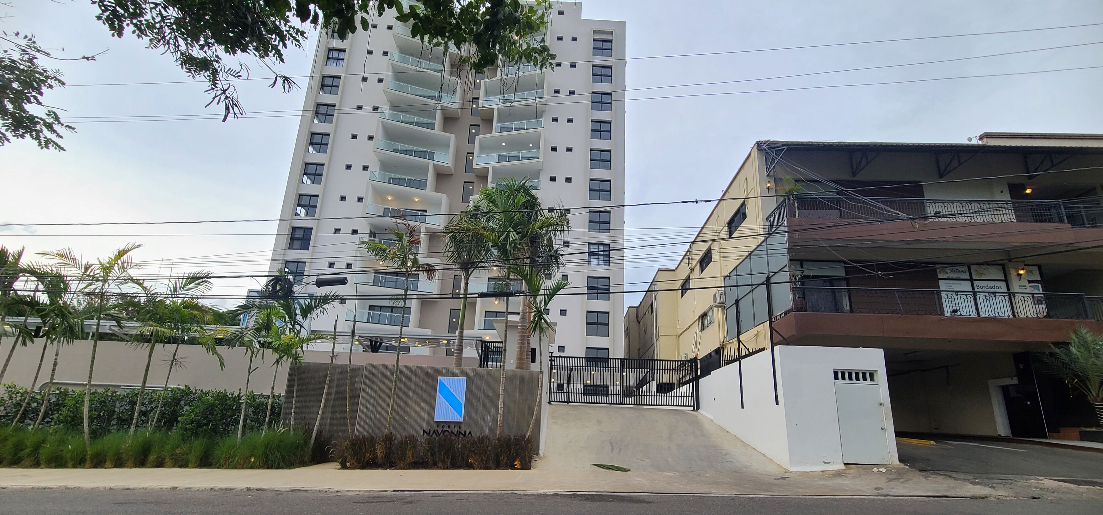 A multi-story residential building with balconies, a gated entrance, and a parking structure.