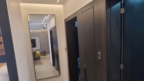 A modern hallway with a mirror reflecting a room, dark wooden doors, and a light-colored floor. - De Lujo a dos minutos del Monumento (Santiago de los Caballeros)