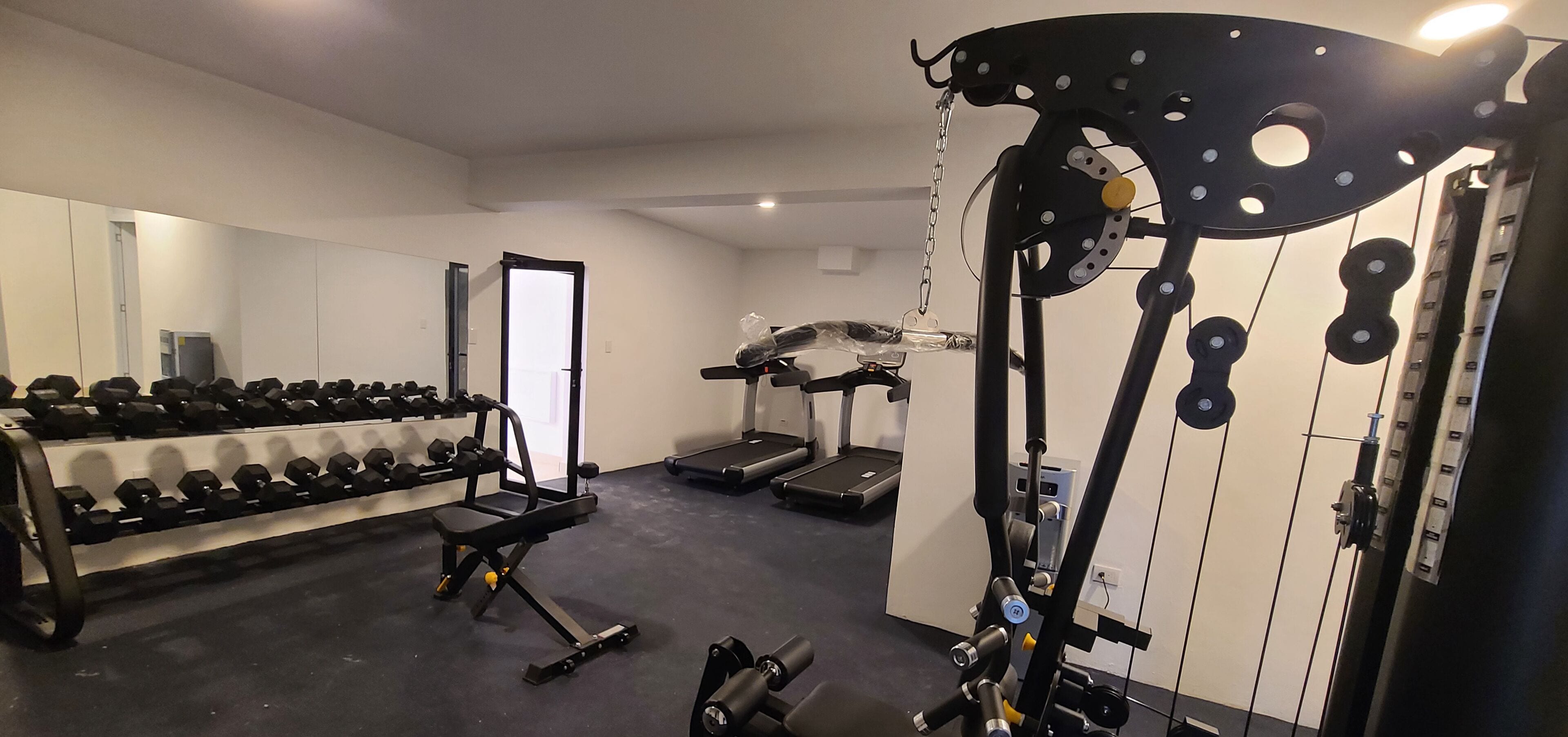 Uma academia com halteres, esteiras e aparelhos de musculação.