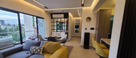 A modern living room with a sofa, a dining area, and a kitchen.