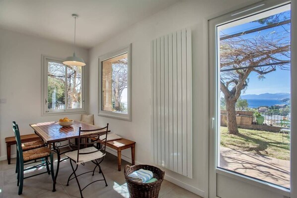 A dining area with a table, chairs, and a view of the outdoors.