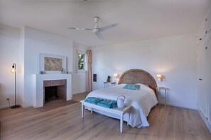 A bedroom with a bed, a fireplace, a ceiling fan, and bedside lamps. - Casa Marinu Muntese (Brando)