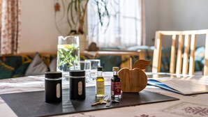 Una mesa con una alfombra negra, una jarra de cristal, una botella de aceite de oliva, una botella de vino tinto, un bloque de cuchillos de madera y llaves.