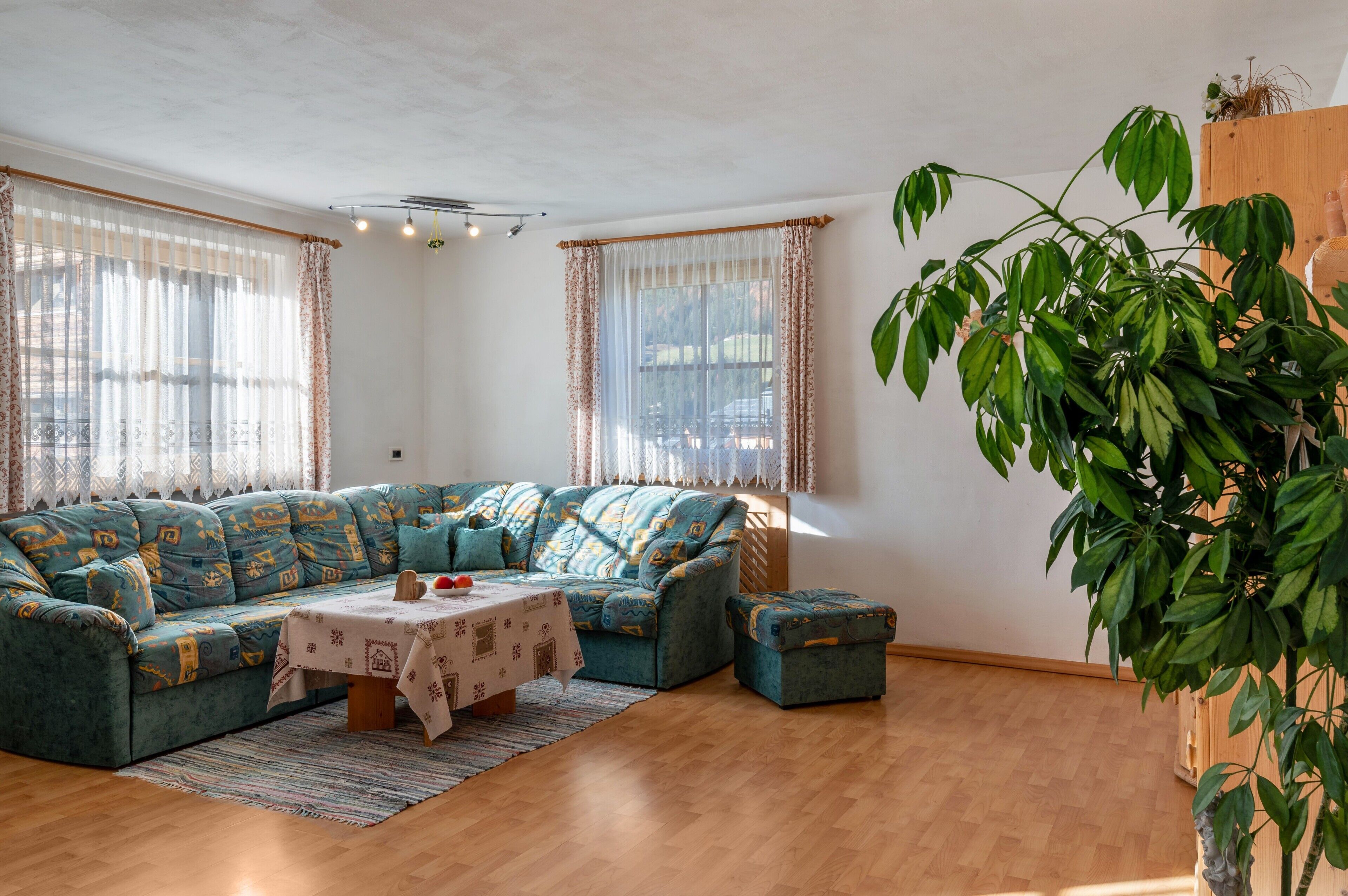 Een woonkamer met een bank, een tafel met tafelkleed en een potplant.