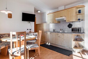 Una cocina compacta con armarios de madera, un microondas y un televisor de pantalla plana.