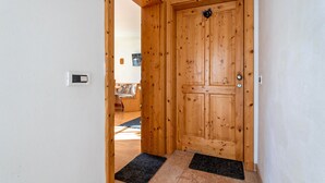 Una puerta de madera con una placa de número, un felpudo y un interruptor de luz en la pared.