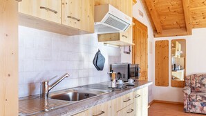 Una cocina con armarios de madera, un lavamanos de acero inoxidable, un microondas y una cafetera.