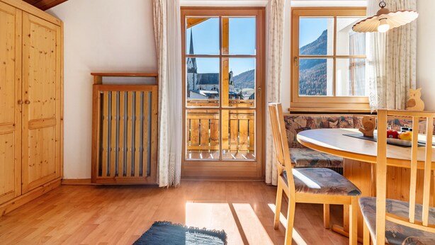 Un interior de madera con comedor, vista por una ventana y puerta de madera.