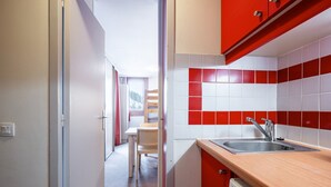 A kitchen with red and white tiles, a wooden countertop, and a stainless steel sink.