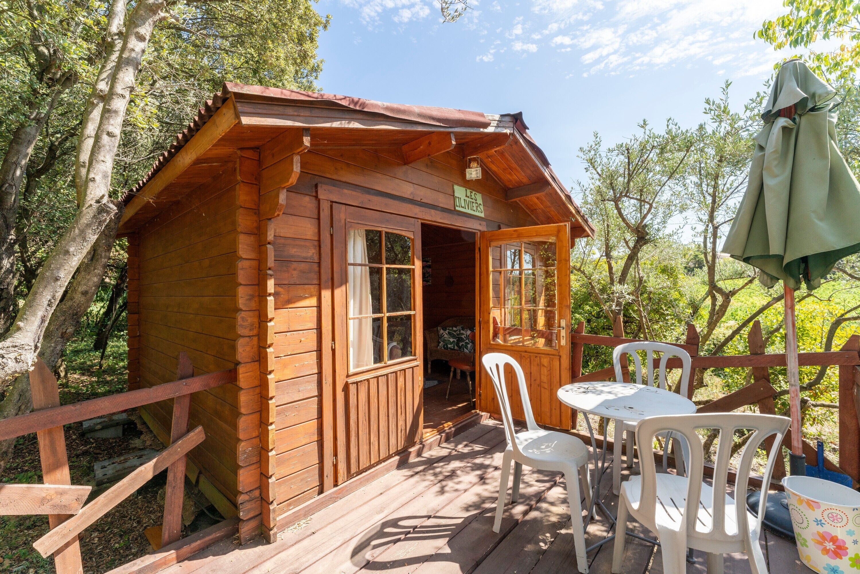 Eine Holzhütte mit Veranda, einem Tisch, Stühlen und einem Sonnenschirm.