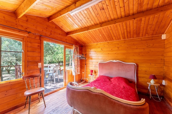 Une pièce dans une cabane en bois, comprenant un lit, une chaise et une fenêtre.