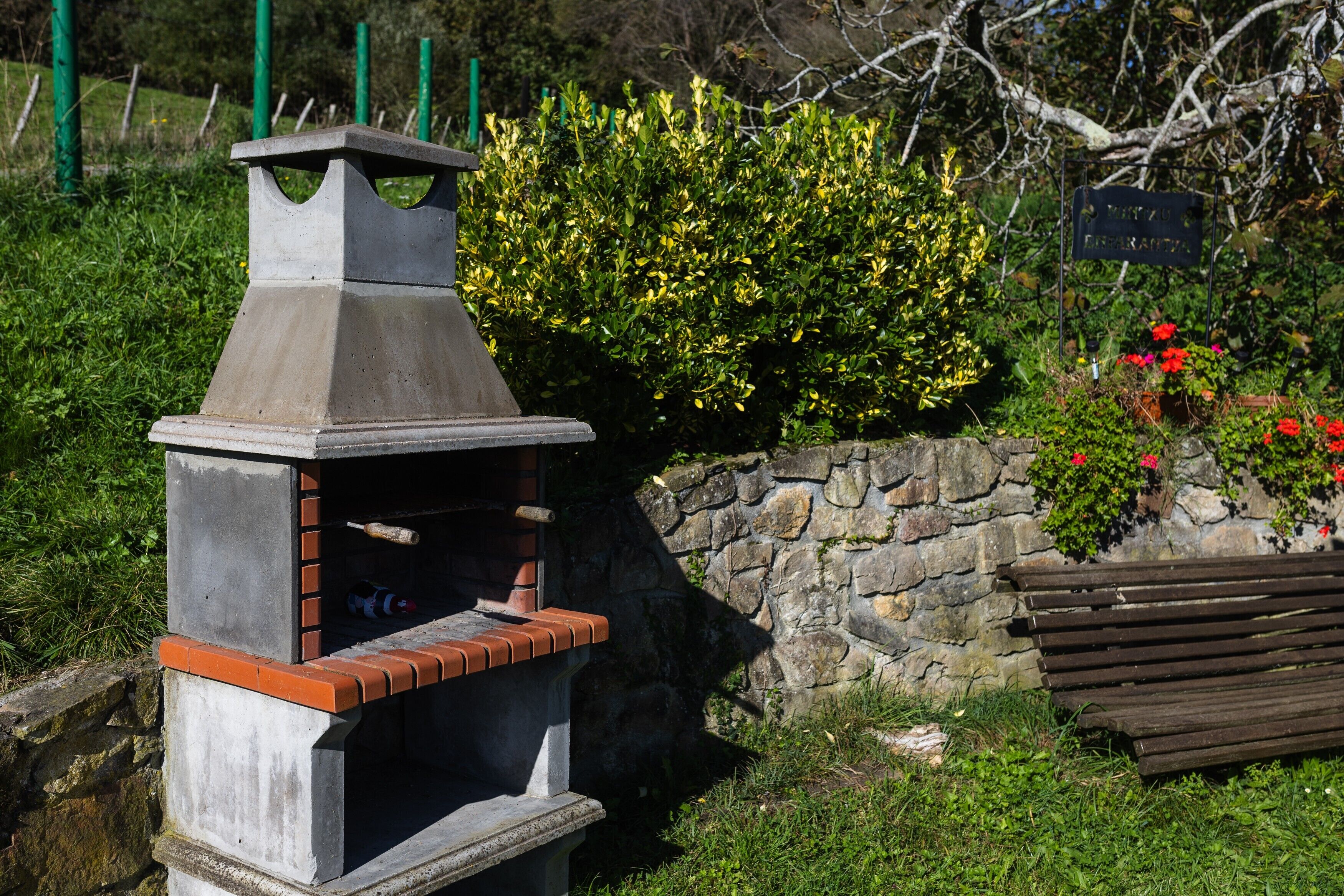 A stone wall with a brick oven and a wooden bench.