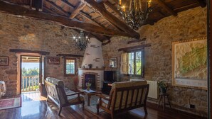 Interior rústico de piedra con muebles de madera, chimenea y una lámpara de araña.