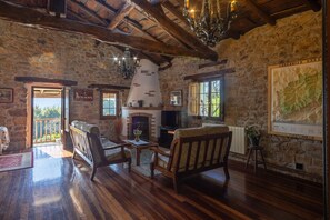 A rustic stone interior with wooden furniture, a fireplace, and a chandelier.