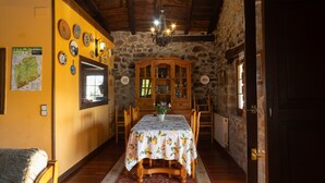 Un comedor con una mesa lista para dos personas, una pared de piedra y un mueble de madera.
