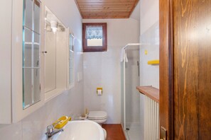 A bathroom with a toilet, a shower, and a sink.