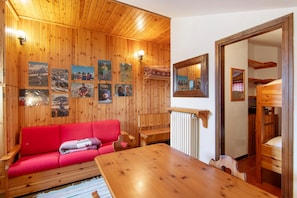 A wooden-paneled room with a red sofa, a wooden table, and a mirror.